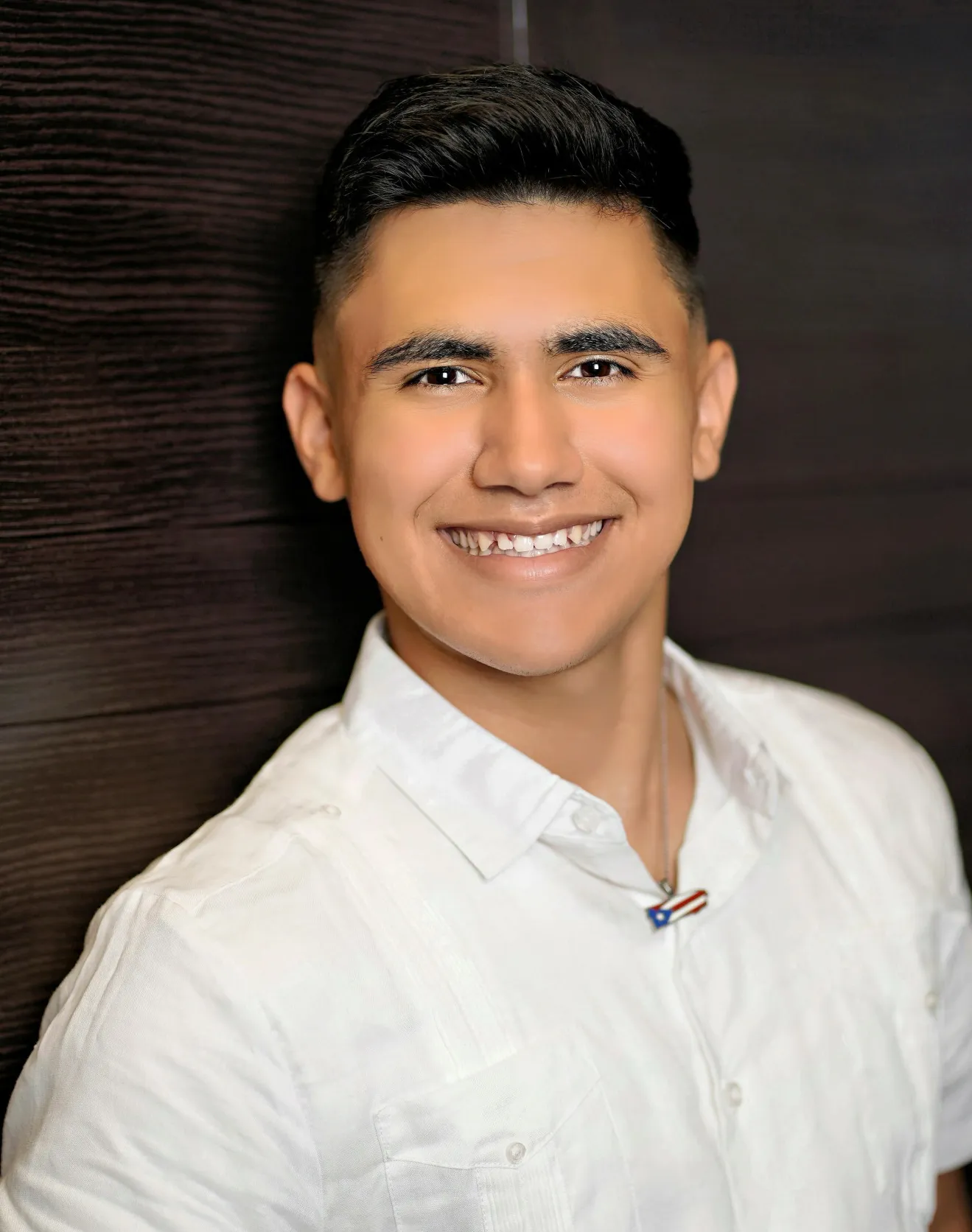 An individual wearing a white shirt, posing for a portrait.