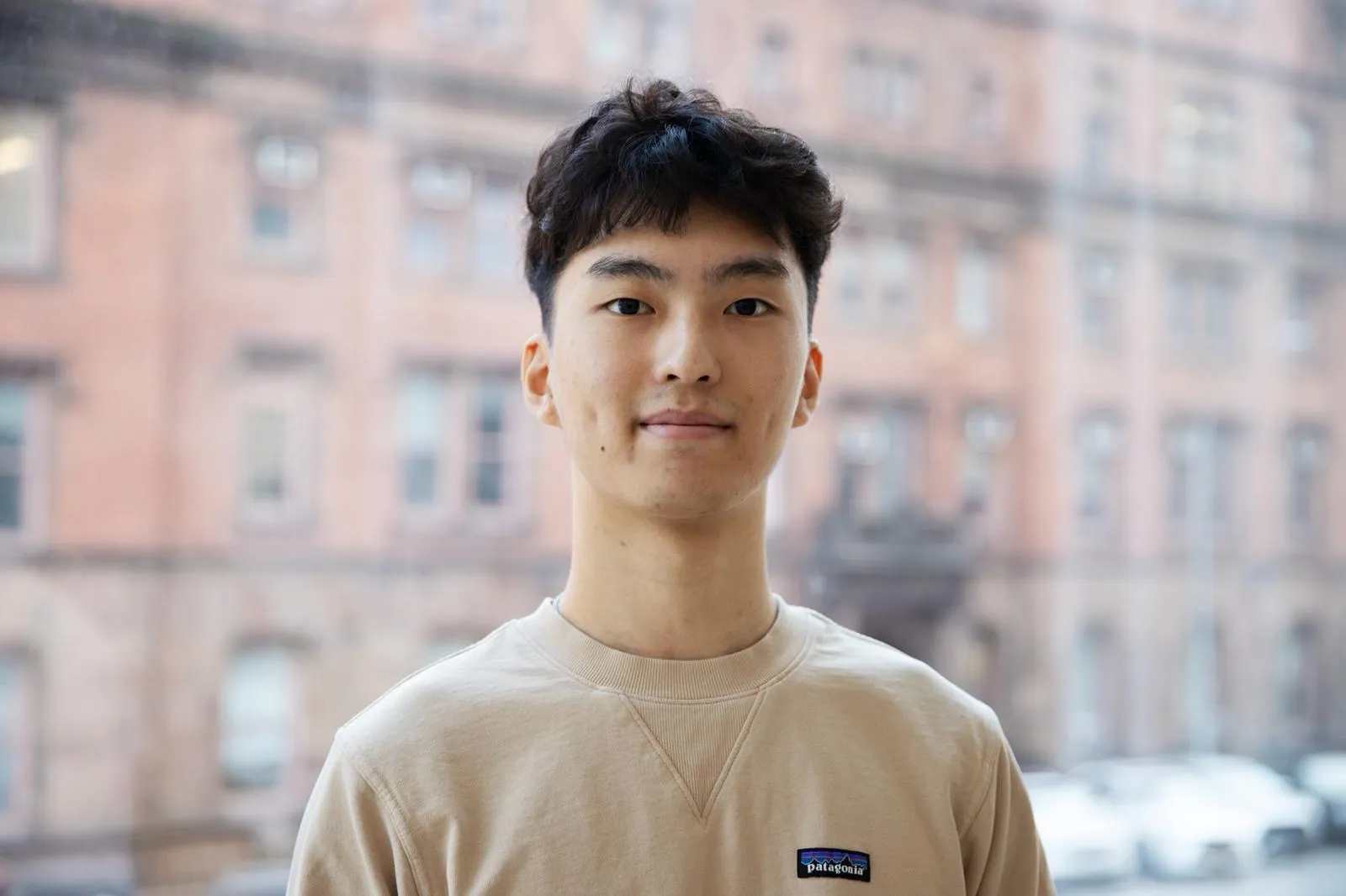 A male in a tan shirt, posing for a photo. 