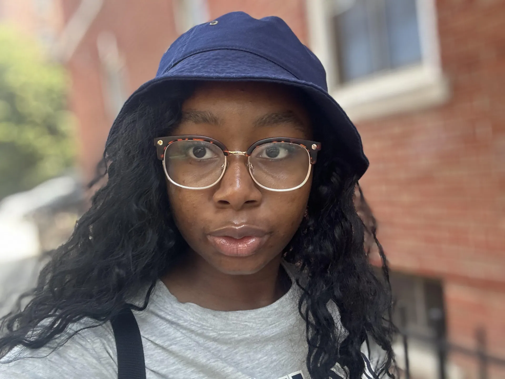 Individual with a hat and glasses, posing for a selfie. 